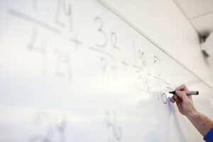 Teacher solving mathematical equation on whiteboard